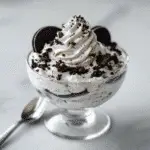 High protein Oreo fluff in a dessert bowl topped with crushed Oreos