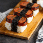 Close-up of pepper-glazed Spam musubi wrapped in seaweed over white rice