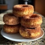 A stack of freshly made Apple Cider Donuts coated in cinnamon sugar.