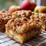 Close-up of a Caramel Apple Bar with a gooey caramel drizzle and crumble topping, showing layers of apple filling.