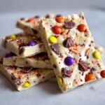 A stack of white chocolate Halloween Candy Bark pieces, topped with colorful candies and sprinkles.
