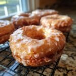 Close-up of freshly made Maple Glazed Donuts cooling on a wire rack. The glaze is thick and shiny.