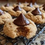 Close-up of a delicious Peanut Butter Blossom cookie with a bite taken out, topped with a chocolate kiss.