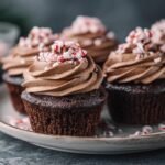 Close-up of chocolate Peppermint Mocha Cupcakes topped with swirled chocolate frosting and crushed candy canes.