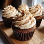 Close-up of a Pumpkin Spice Latte Cupcake topped with creamy frosting and a dusting of cinnamon.