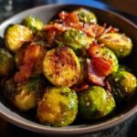 Close-up of roasted Brussels sprouts with crispy bacon pieces in a bowl.