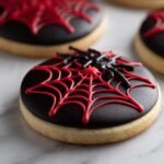 Close-up of a Spooky Spider Cookie decorated with black frosting, a red spider web, and a black spider.