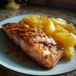 A perfectly grilled salmon fillet served with juicy pineapple chunks on a blue plate.