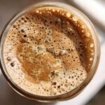 Top-down view of a jar of High Protein Overnight Oats with a rich, frothy, coffee-colored topping.