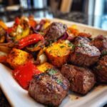 Close-up of Whole30 steak bites with roasted sweet potatoes, red and yellow bell peppers, and red onion, garnished with parsley.