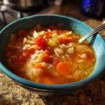 A vibrant bowl of homemade Cabbage Soup with visible cabbage, carrots, and tomatoes.