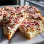 Close-up of Candy Cane Pizza slices with melted mozzarella and crushed candy canes on a marble surface.