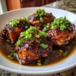 Close-up of Caramelised Soy Chicken in Garlic Ginger Broth, garnished with scallions, in a white bowl.