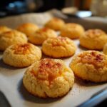 Close-up of freshly baked Cheesy Thumbprint Appetizers on a baking sheet, sprinkled with paprika.