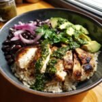 A vibrant Chimichurri Grilled Chicken Bowl with Garlic Sauce, featuring rice, chicken, beans, avocado, and red onion.
