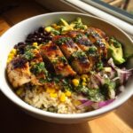 A vibrant Chimichurri Grilled Chicken Bowl with Garlic Sauce, featuring rice, corn, beans, avocado, and red onion.