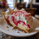 A slice of Christmas Peppermint Pie with a graham cracker crust, peppermint swirl filling, and crushed peppermint topping.