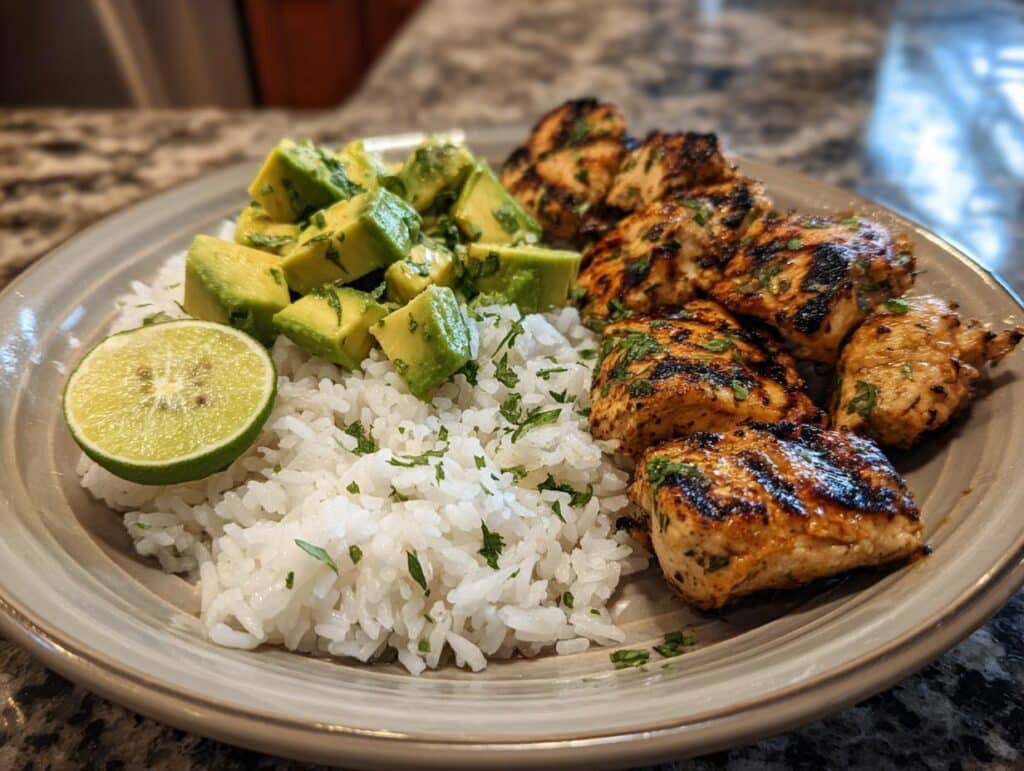 Plate of Zesty Cilantro Lime Chicken with Avocado and Jasmine Rice. Grilled chicken, avocado, rice, and lime.