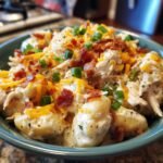 A bowl of Creamy Crack Chicken Gnocchi, topped with bacon, shredded cheese, and green onions.