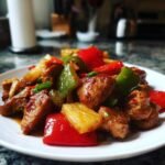 A plate of Crockpot Sweet and Sour Chicken with colorful bell peppers and pineapple chunks.