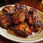 Close-up of a plate of spicy Firecracker Chicken, glistening with sauce and garnished with herbs.