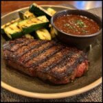 A delicious Grilled Steak Bowl with Sauce and Grilled Zucchini on a plate, ready to eat.