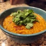 A vibrant bowl of Lentil Curry, garnished with fresh cilantro, ready to be served.