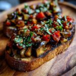 Two pieces of Low Carb Aubergine Bruschetta topped with tomatoes and basil on a wooden board.