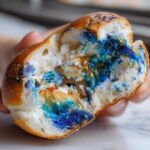 Close-up of a half-eaten Marbled Blueberry Bagel, showing the blue swirls and golden highlights inside.
