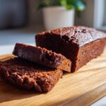 Delicious slices of moist chocolate loaf cake on a wooden board, ready to eat.