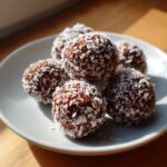 A plate of delicious No-Bake Dubai Chocolate Balls, coated in shredded coconut.