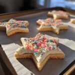 Star-shaped No Stick No Chill Christmas Cookie with white frosting and colorful sprinkles on a baking sheet.