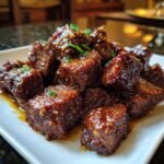 Close-up of Slow Cooker Garlic Butter Beef Bites on a white plate, garnished with green onions.