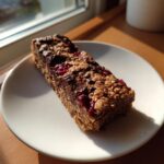 A single Speculoos Chocolate Cherry Bar on a white plate, showcasing the layers of chocolate and cherries.