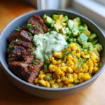 Close-up of a Steak & Avocado Roasted Corn Bowl with Cilantro Cream Sauce, featuring steak, avocado, and corn.