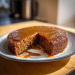 Delicious Sticky Toffee Pudding Cake with a slice missing, drizzled with caramel sauce.