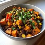 A vibrant Sweet Potato Beef Bowl filled with sweet potatoes, beef, black beans, corn, and fresh cilantro.