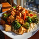 A plate of Teriyaki Chicken Casserole with broccoli, carrots, and rice, topped with sesame seeds.