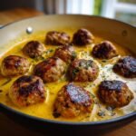 Delicious Turkey Meatballs in Pumpkin Sage Sauce, simmered in a pan with fresh herbs.