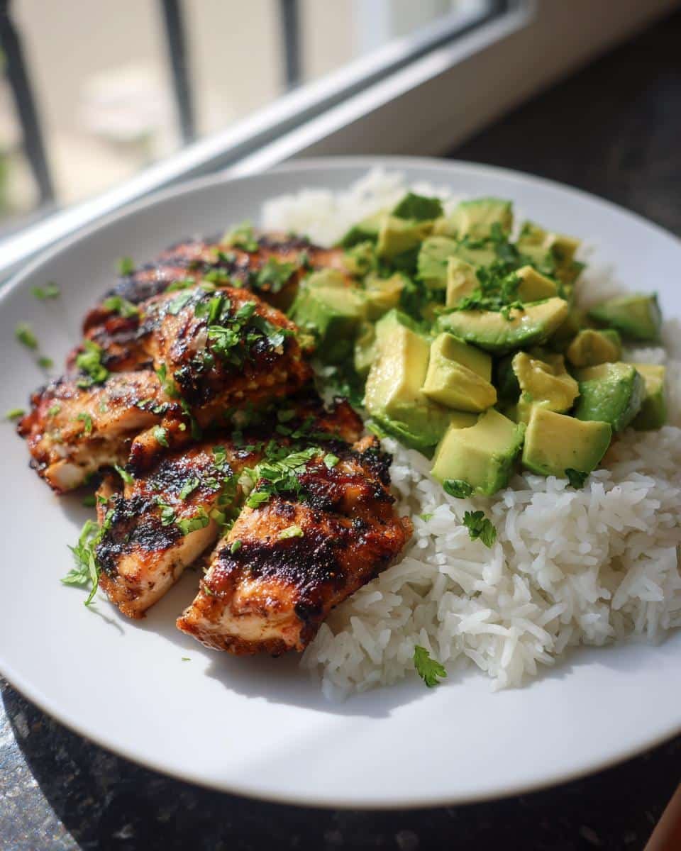 Zesty Cilantro Lime Chicken: 40-Minute Flavor Bomb 7 A plate of Zesty Cilantro Lime Chicken with Avocado and Jasmine Rice, garnished with cilantro.
