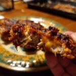 Close-up of a piece of Baked Ranch Chicken, showing the juicy interior and crispy coating.