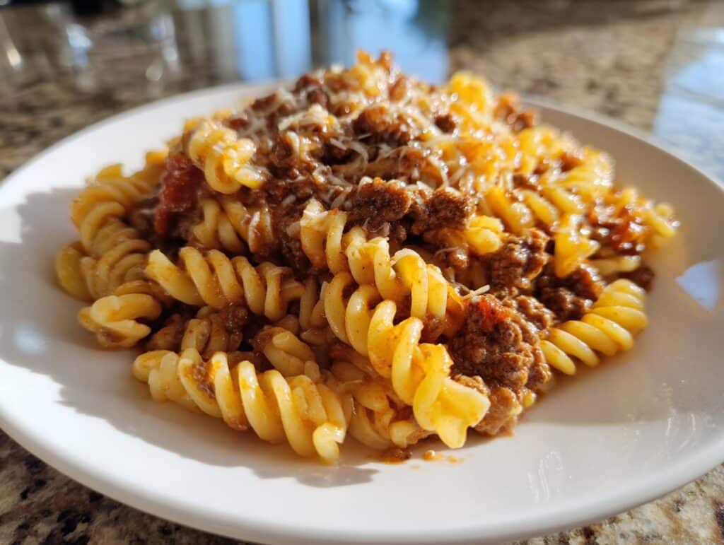 A plate of Beef and Rotini in Garlic Parmesan Sauce, topped with cheese.