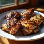 Close-up of Bobby Flay Chicken Thighs, grilled and seasoned, served on a white plate.