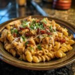 A plate of Cajun Garlic Chicken Rotini, garnished with herbs, cheese, and spices.