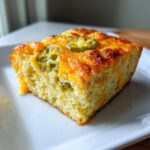 A slice of Cheesy Hatch Chile Cornbread with a spicy kick, topped with melted cheese and hatch chile slices.