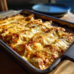 A pan filled with freshly baked Chicken Enchiladas Bake, topped with melted cheese.