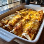 Close up of a casserole dish filled with Chicken Enchiladas with Sour Cream White Sauce, topped with melted cheese.
