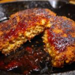 Close-up of a delicious Country Fried Steak cut in half, topped with rich gravy.