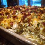Close-up of Crack Chicken Casserole with chicken, noodles, cheese, bacon, and herbs in a baking dish.