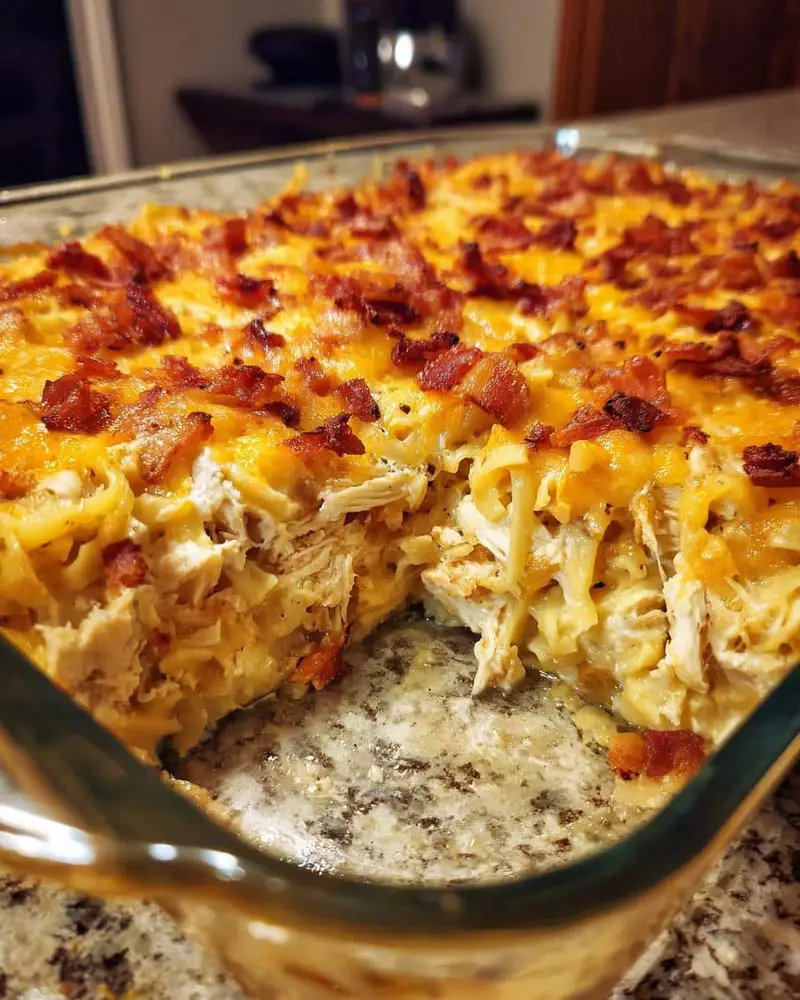 Irresistible Crack Chicken Casserole Recipe: Just 4 Steps 6 Close-up of a cheesy Crack Chicken Casserole in a glass baking dish, topped with bacon.